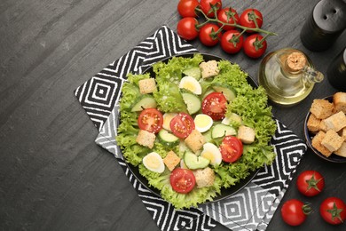 Photo of Delicious salad with croutons and ingredients on black table, flat lay. Space for text
