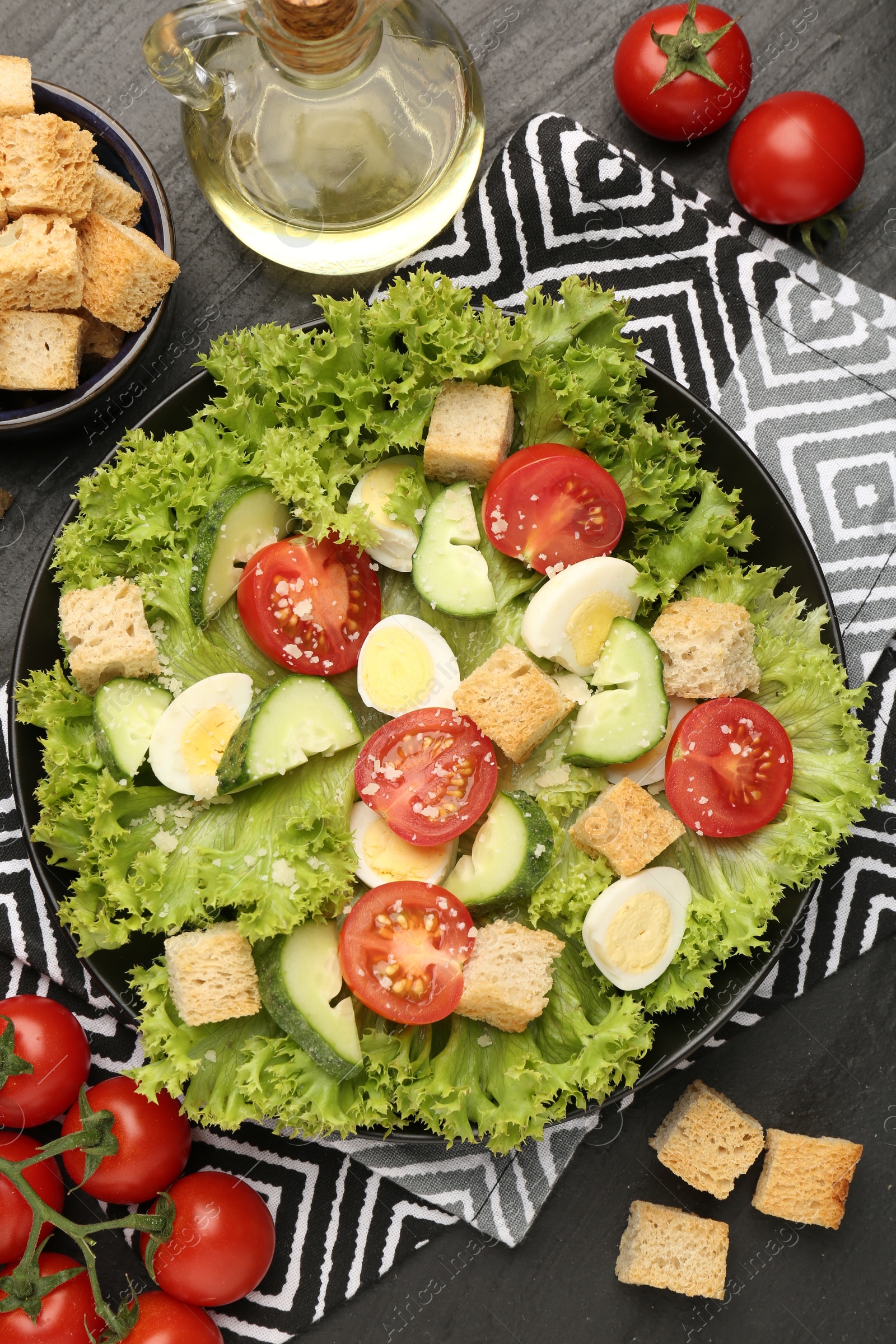 Photo of Delicious salad with croutons and ingredients on black table, flat lay