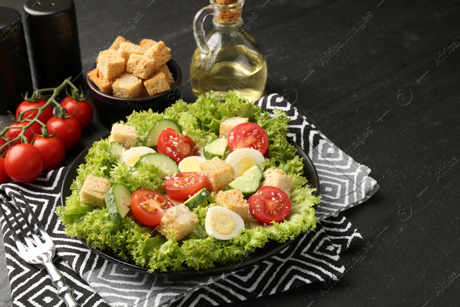 Photo of Delicious salad with croutons and ingredients on black table, closeup. Space for text