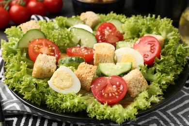 Photo of Delicious salad with croutons, chicken, quail eggs, vegetables and cheese on table, closeup