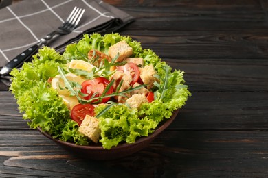 Photo of Delicious salad with croutons, chicken, egg, vegetables, lemon and arugula on wooden table, closeup. Space for text