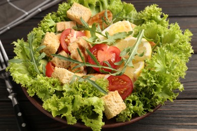 Photo of Delicious salad with croutons, chicken, egg, vegetables, lemon and arugula on wooden table, closeup