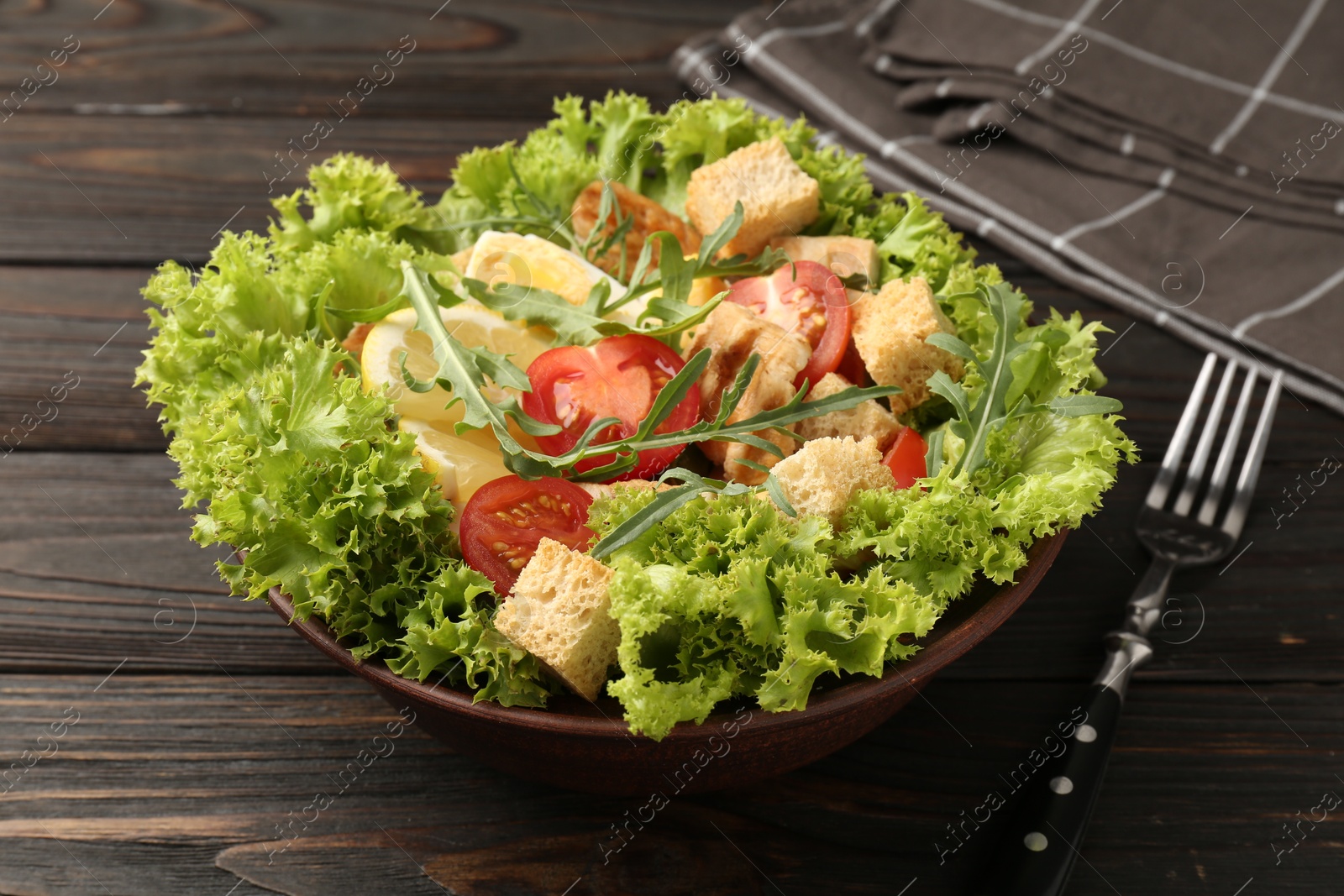 Photo of Delicious salad with croutons, chicken, egg, vegetables, lemon and arugula on wooden table, closeup