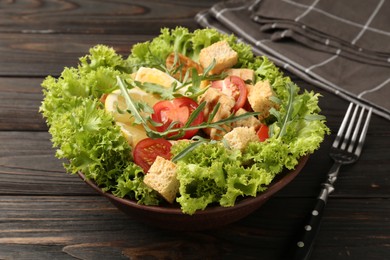 Photo of Delicious salad with croutons, chicken, egg, vegetables, lemon and arugula on wooden table, closeup