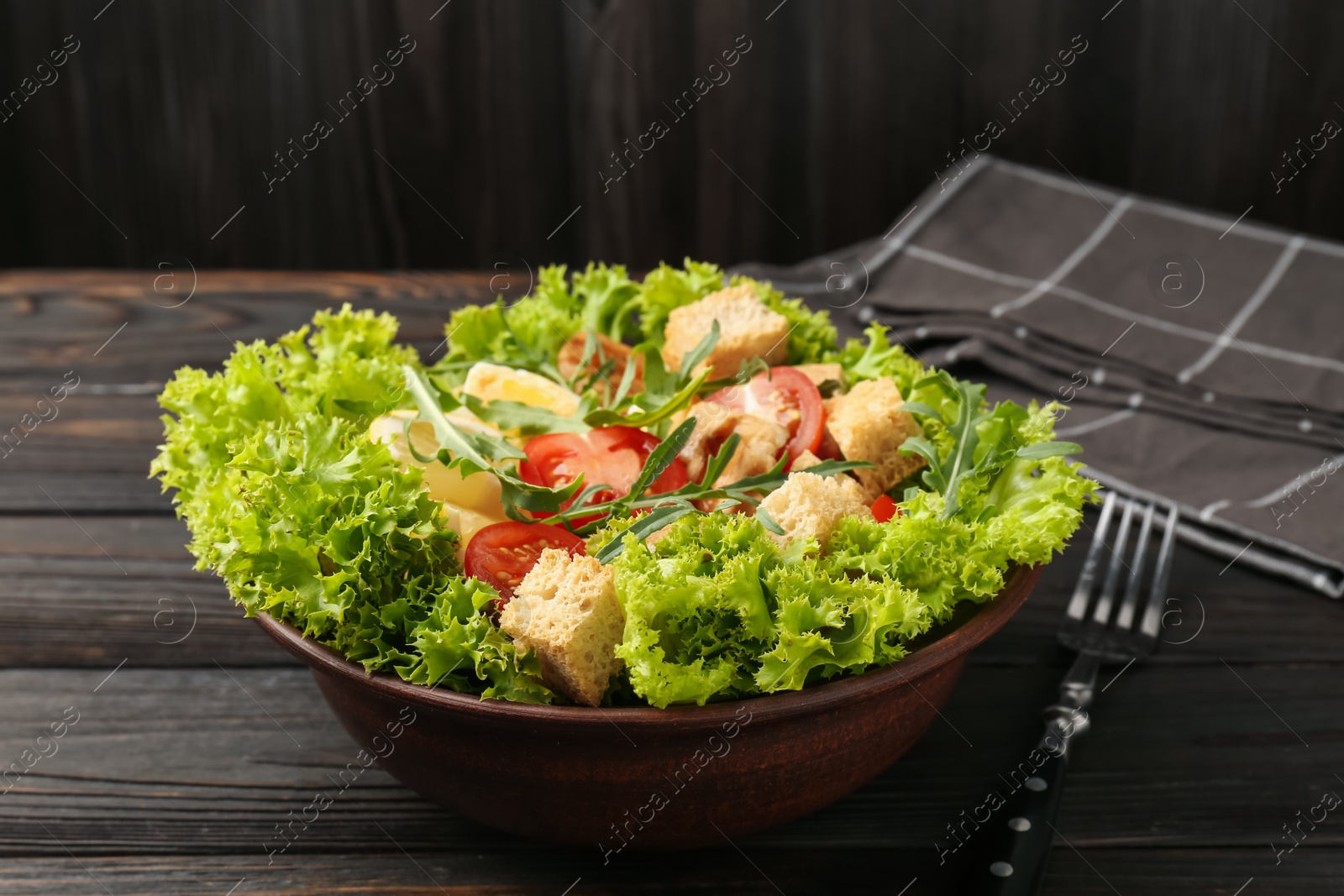 Photo of Delicious salad with croutons, chicken, egg, vegetables, lemon and arugula on wooden table, closeup