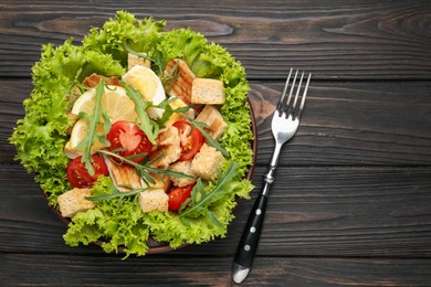 Photo of Delicious salad with croutons, chicken, egg, vegetables, lemon and arugula on wooden table, flat lay. Space for text