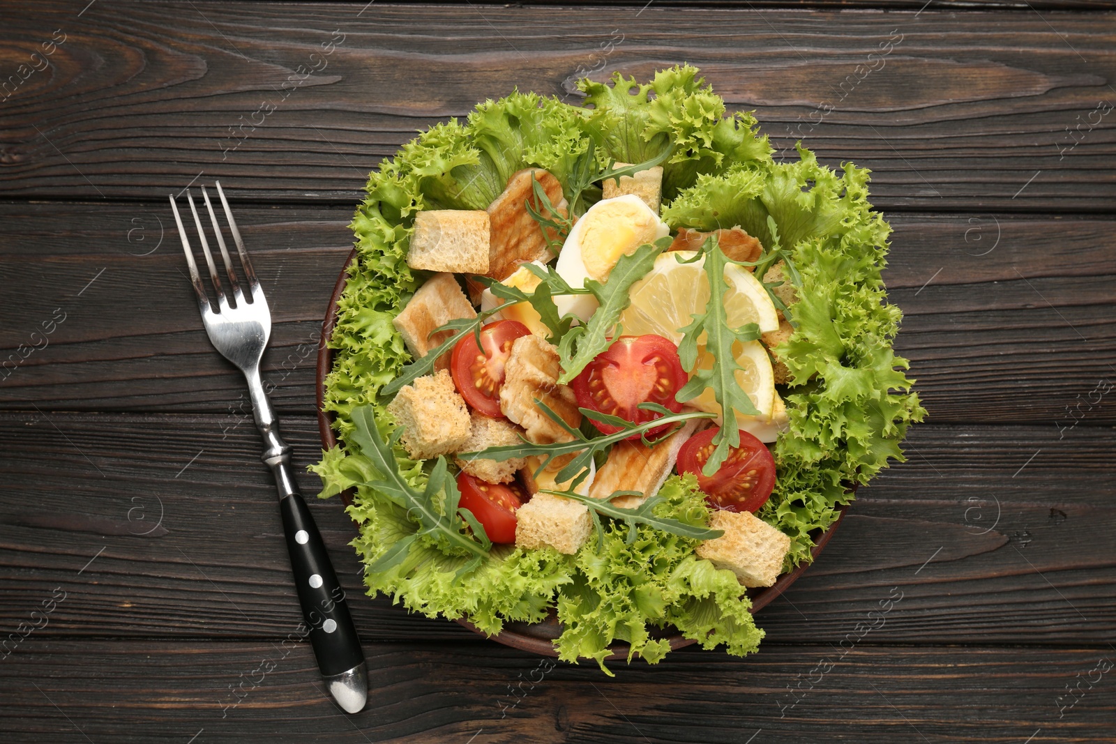 Photo of Delicious salad with croutons, chicken, egg, vegetables, lemon and arugula on wooden table, flat lay