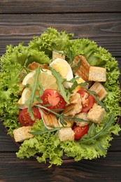 Photo of Delicious salad with croutons, chicken, egg, vegetables, lemon and arugula on wooden table, top view