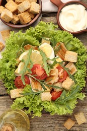 Photo of Delicious salad with croutons served on wooden table, flat lay
