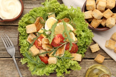 Photo of Delicious salad with croutons served on wooden table, flat lay