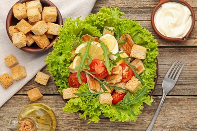 Photo of Delicious salad with croutons served on wooden table, flat lay