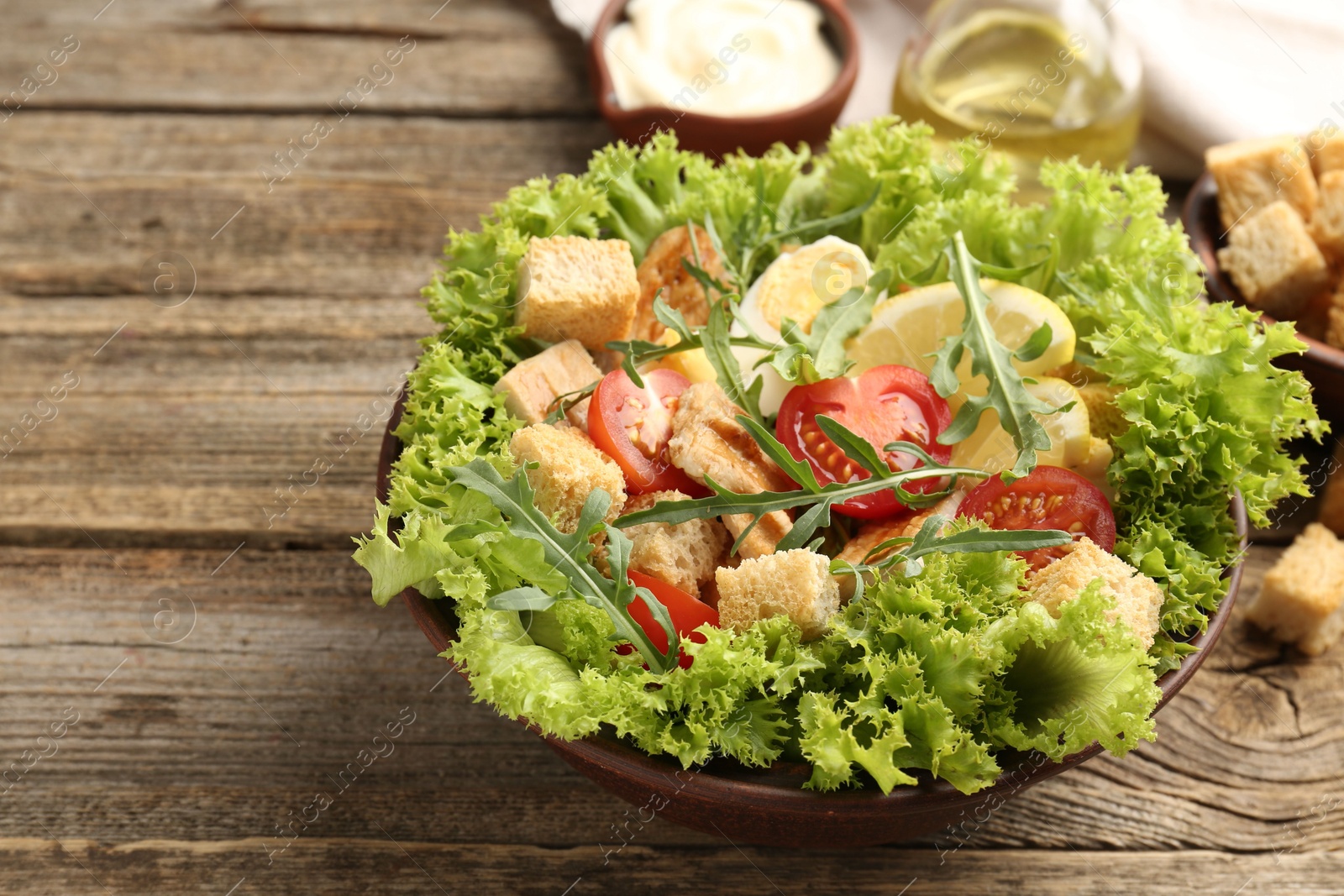 Photo of Delicious salad with croutons served on wooden table, closeup. Space for text