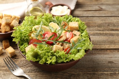 Photo of Delicious salad with croutons served on wooden table, closeup. Space for text