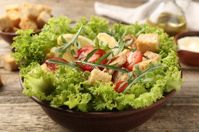 Photo of Delicious salad with croutons served on wooden table, closeup