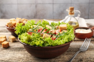 Photo of Delicious salad with croutons served on wooden table, closeup