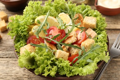 Photo of Delicious salad with croutons served on wooden table, closeup