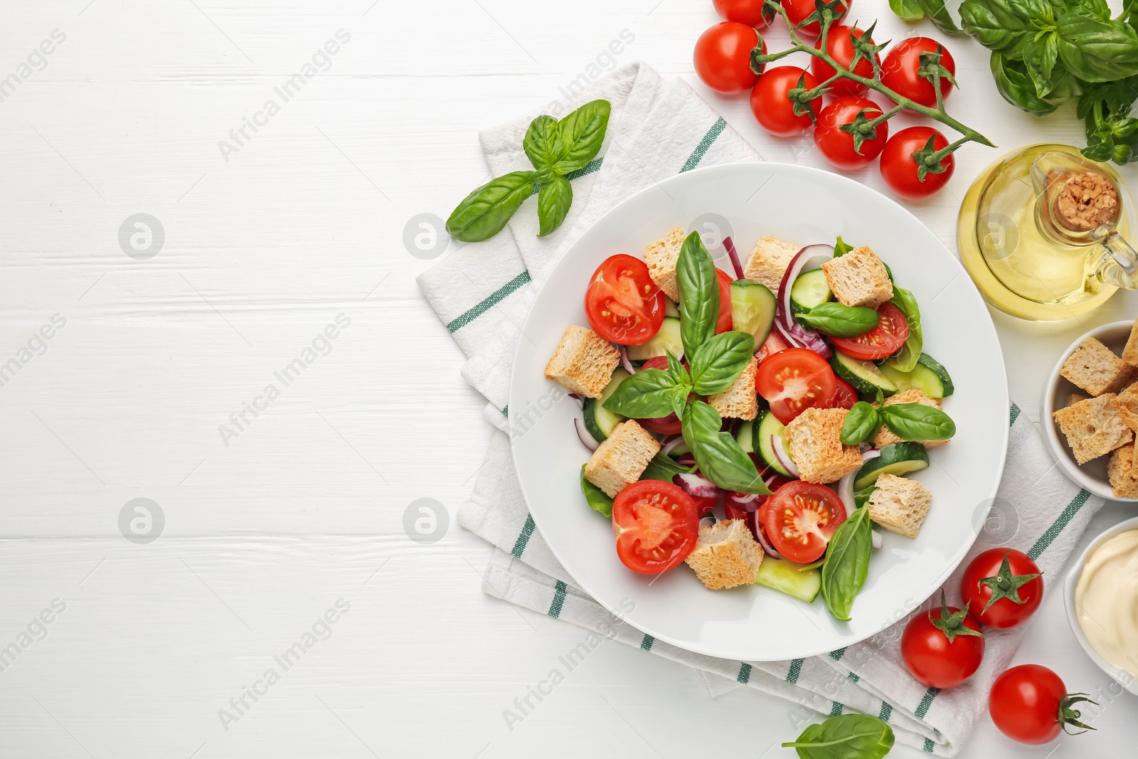 Photo of Delicious salad with croutons and ingredients on white wooden table, flat lay. Space for text