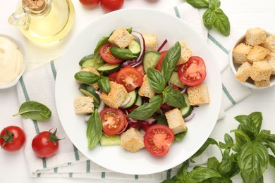 Photo of Delicious salad with croutons and ingredients on white wooden table, flat lay