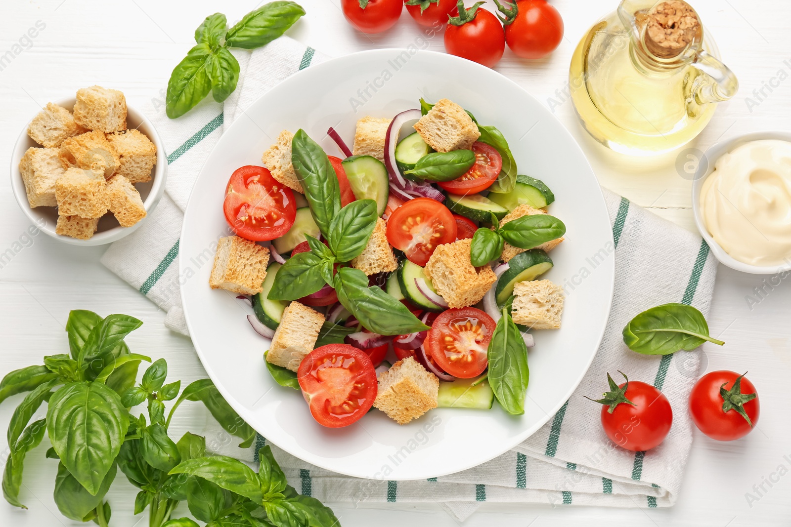 Photo of Delicious salad with croutons and ingredients on white wooden table, flat lay