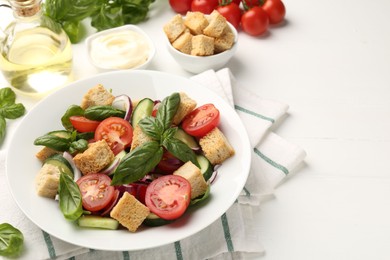 Photo of Delicious salad with croutons and ingredients on white wooden table, closeup