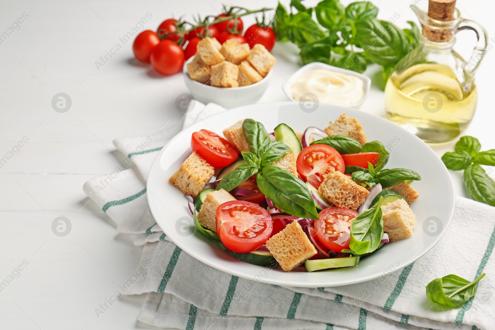 Photo of Delicious salad with croutons and ingredients on white wooden table, closeup
