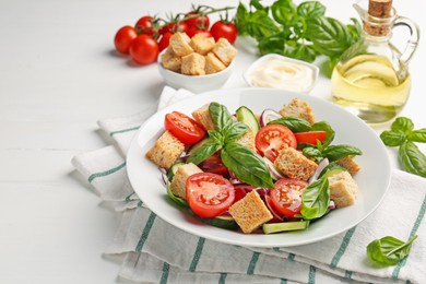 Photo of Delicious salad with croutons and ingredients on white wooden table, closeup