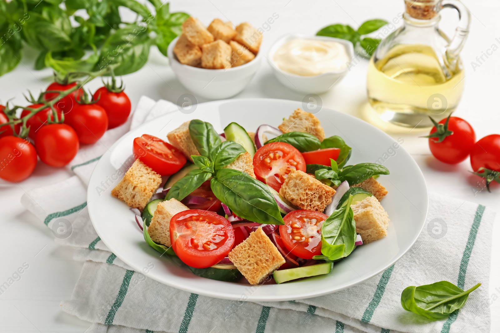Photo of Delicious salad with croutons and ingredients on white wooden table, closeup