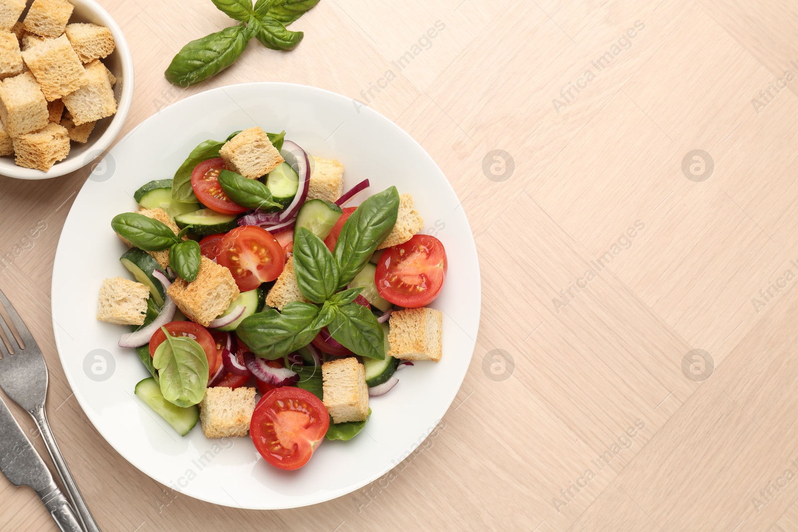 Photo of Delicious salad with croutons, vegetables and basil on wooden table, flat lay. Space for text
