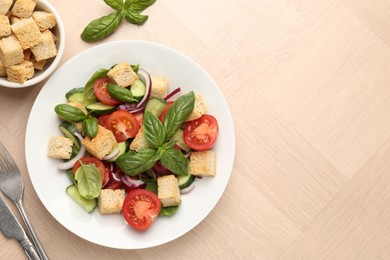 Photo of Delicious salad with croutons, vegetables and basil on wooden table, flat lay. Space for text