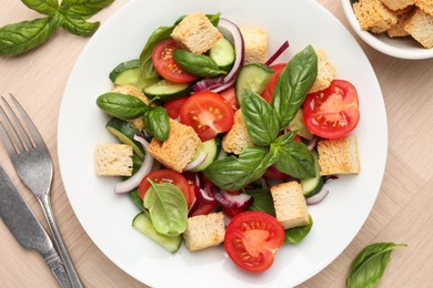 Photo of Delicious salad with croutons, vegetables and basil on wooden table, flat lay