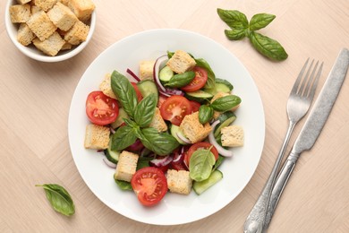 Photo of Delicious salad with croutons, vegetables and basil on wooden table, flat lay