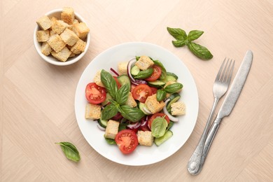 Photo of Delicious salad with croutons, vegetables and basil on wooden table, flat lay