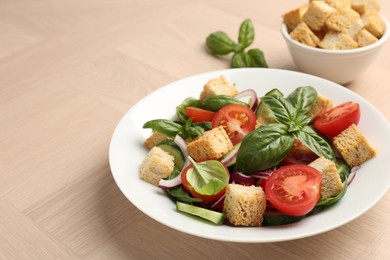 Photo of Delicious salad with croutons, vegetables and basil on wooden table, closeup. Space for text