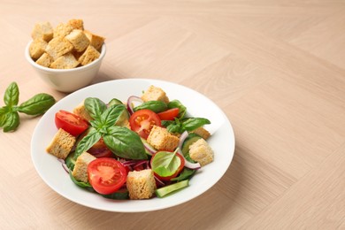 Photo of Delicious salad with croutons, vegetables and basil on wooden table, closeup. Space for text