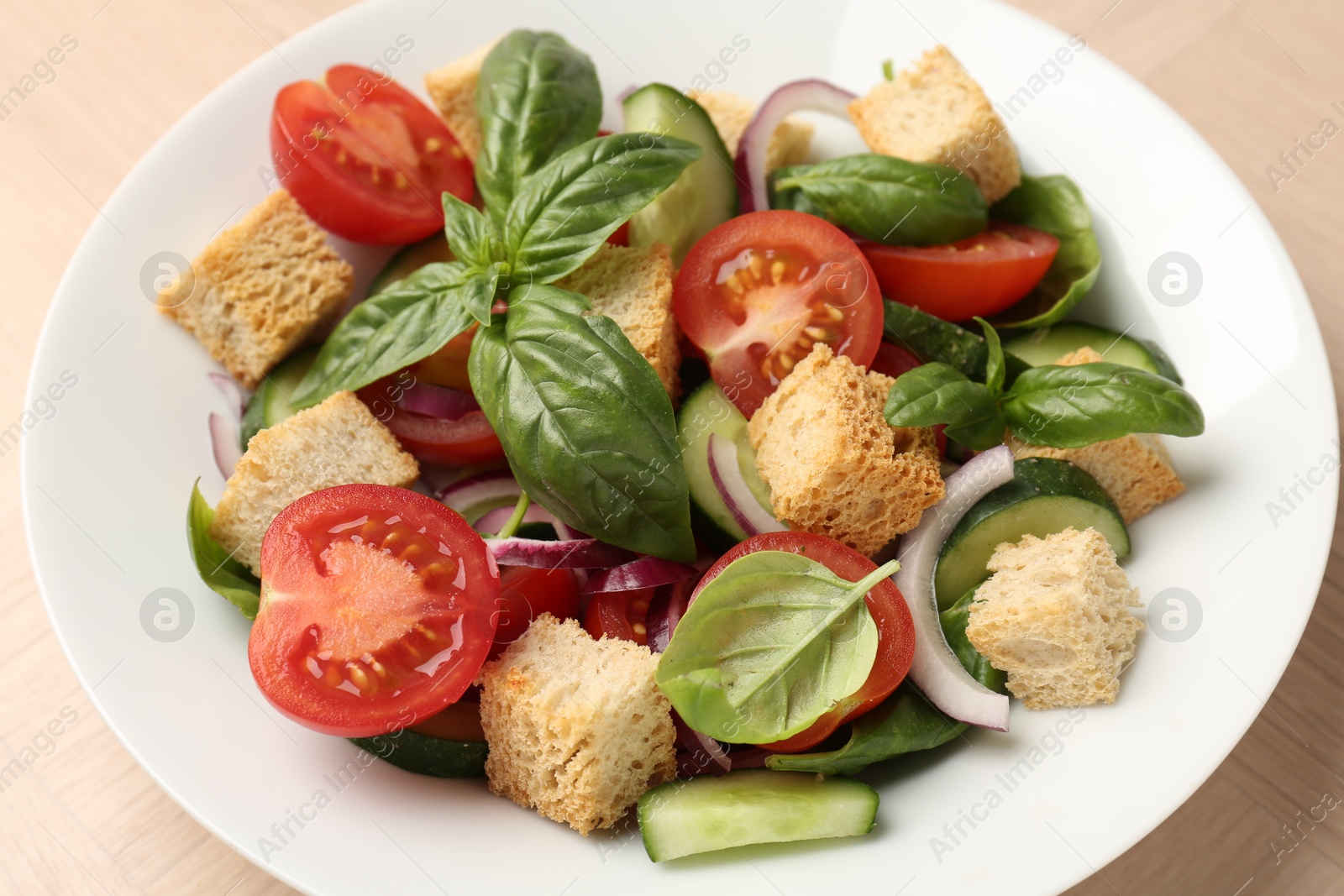 Photo of Delicious salad with croutons, vegetables and basil on table, closeup
