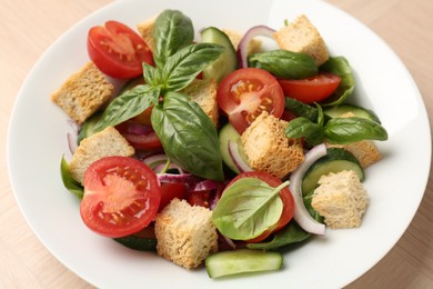 Photo of Delicious salad with croutons, vegetables and basil on table, closeup