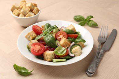 Photo of Delicious salad with croutons, vegetables and basil on wooden table, closeup