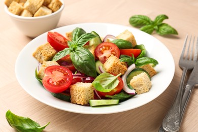Photo of Delicious salad with croutons, vegetables and basil on wooden table, closeup