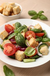 Photo of Delicious salad with croutons, vegetables and basil on wooden table, closeup