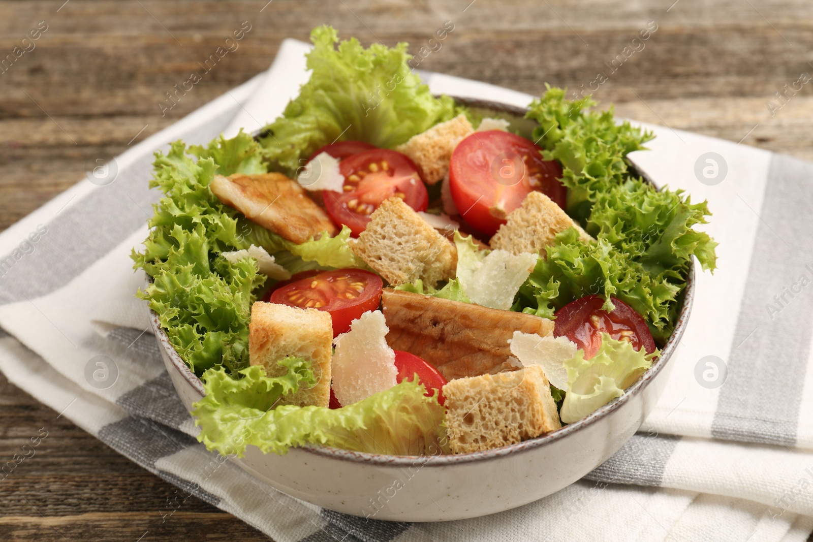Photo of Delicious salad with croutons, chicken, vegetables and cheese on wooden table, closeup