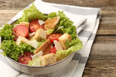 Photo of Delicious salad with croutons, chicken, vegetables and cheese on wooden table, closeup