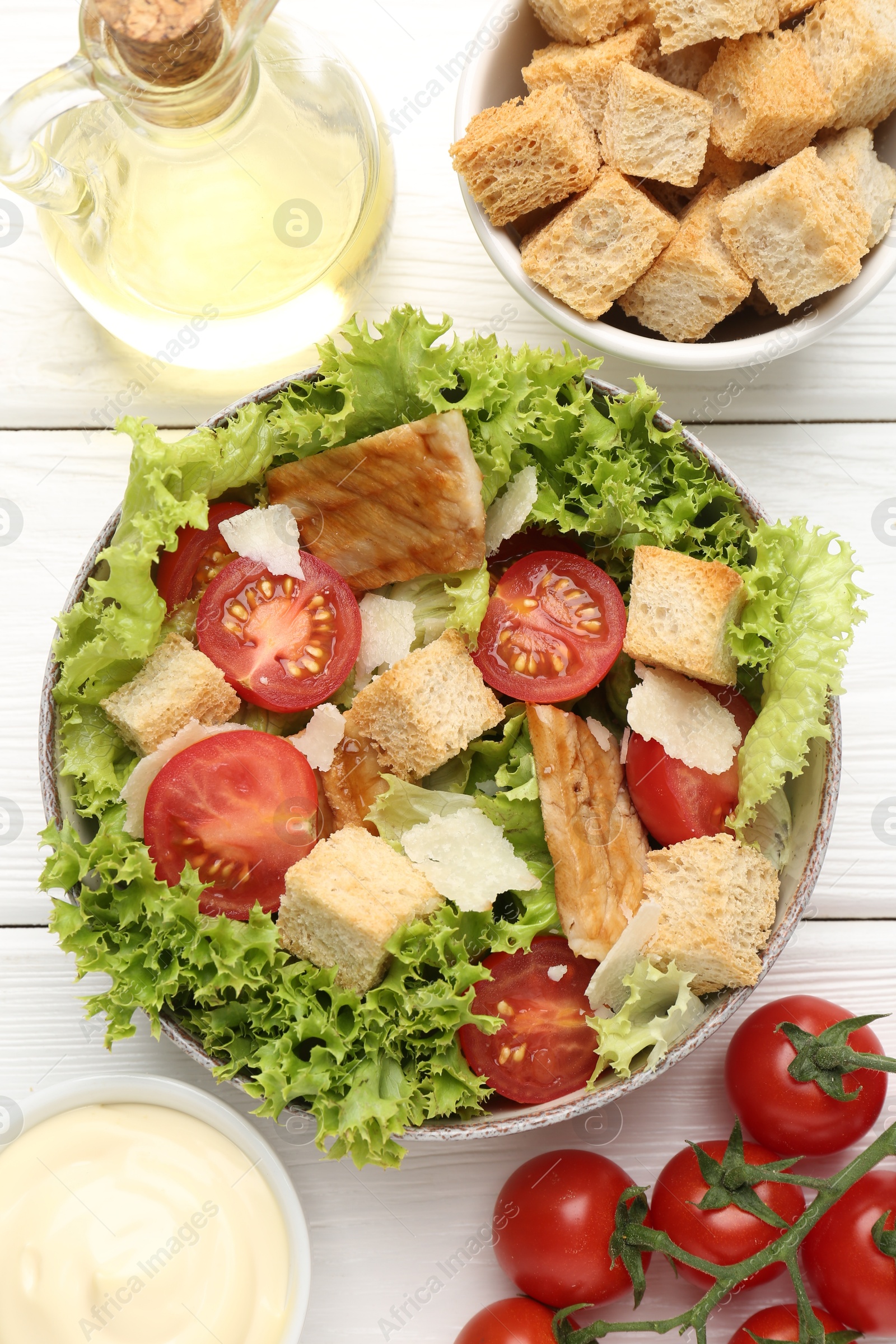 Photo of Delicious salad with croutons and ingredients on white wooden table, flat lay