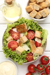 Photo of Delicious salad with croutons and ingredients on white wooden table, flat lay