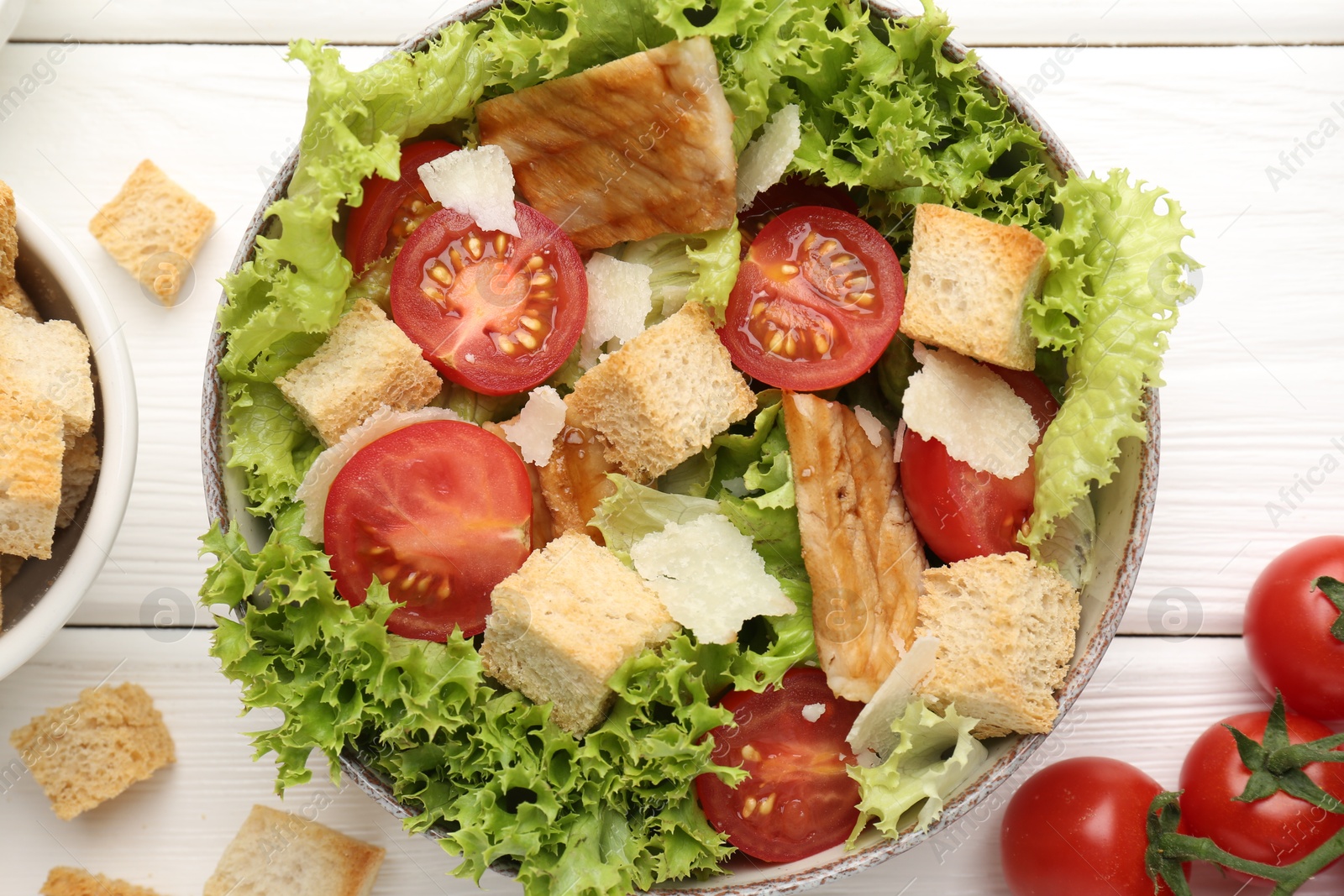 Photo of Delicious salad with croutons and ingredients on white wooden table, flat lay