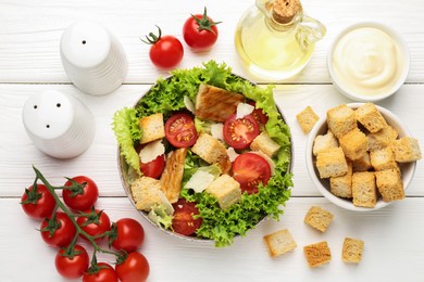 Photo of Delicious salad with croutons and ingredients on white wooden table, flat lay