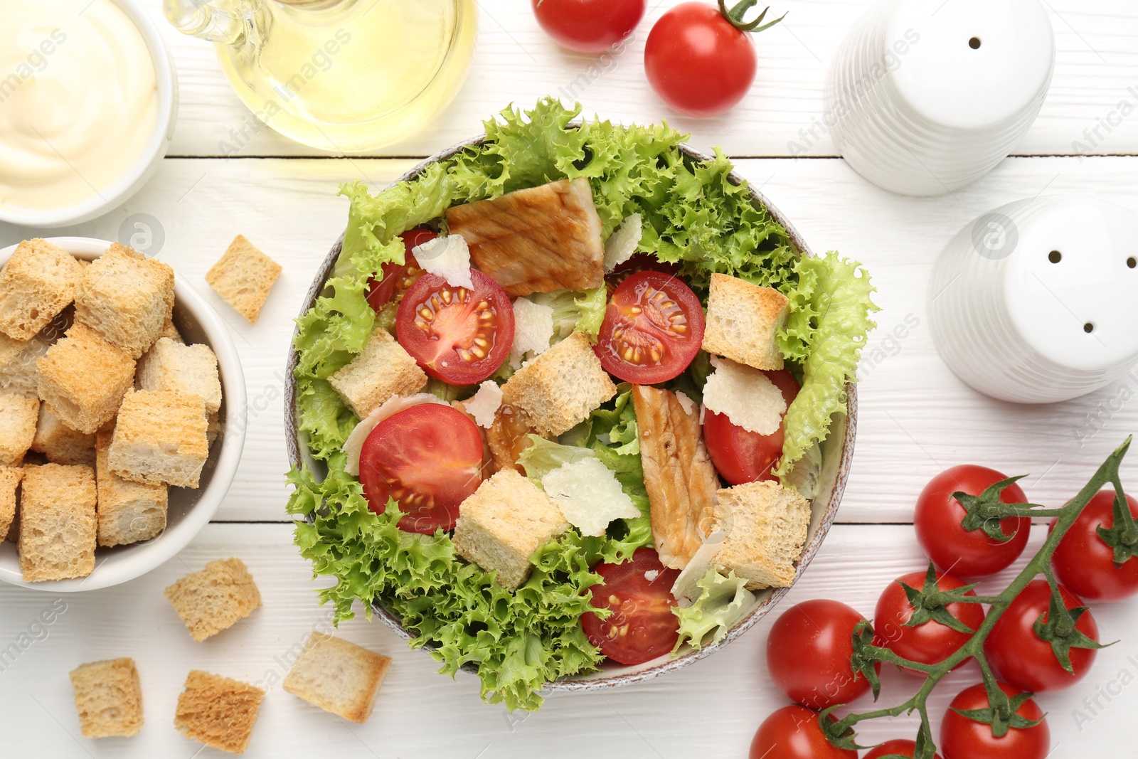 Photo of Delicious salad with croutons and ingredients on white wooden table, flat lay