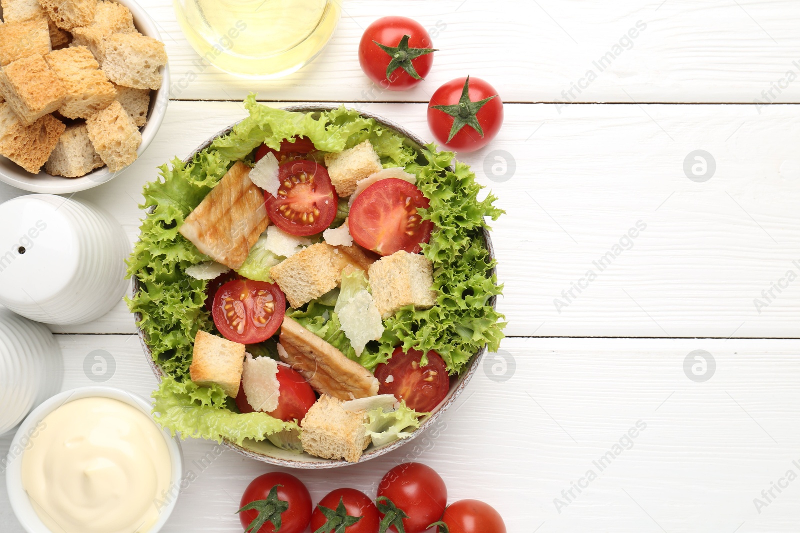 Photo of Delicious salad with croutons and ingredients on white wooden table, flat lay. Space for text