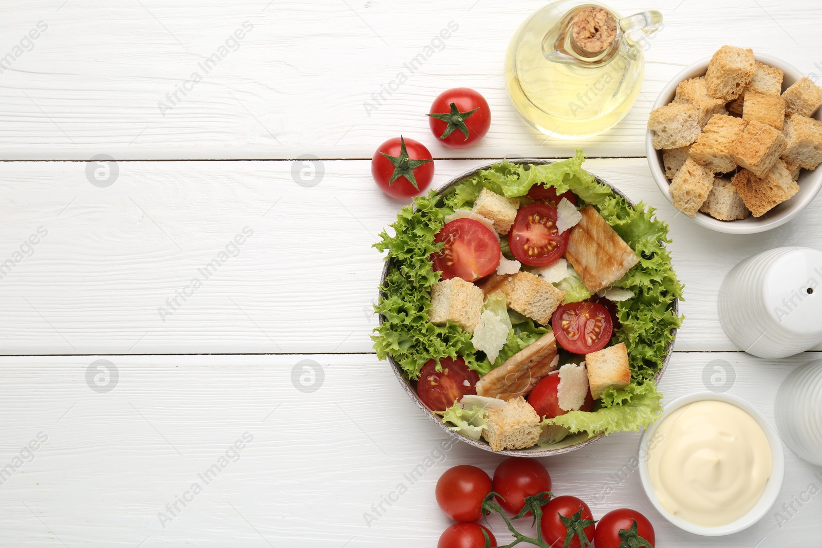 Photo of Delicious salad with croutons and ingredients on white wooden table, flat lay. Space for text