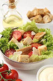 Photo of Delicious salad with croutons and ingredients on white wooden table, closeup