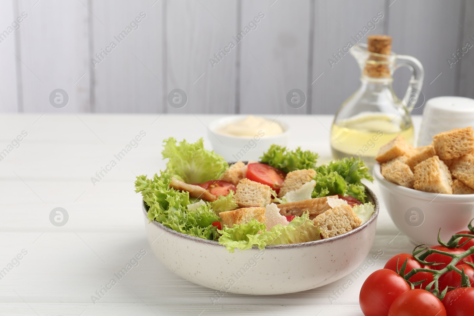 Photo of Delicious salad with croutons and ingredients on white wooden table, closeup. Space for text